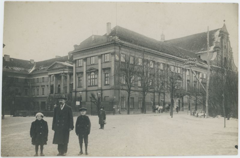 Mężczyzna z dwójką dzieci na tle Pałacu Gubernatorskiego