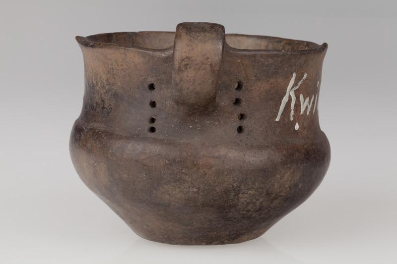 kubek z taśmowatym uchem, obok ucha pionowe rzędy otworków  