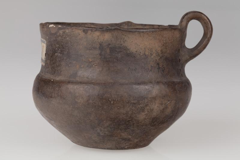 kubek z taśmowatym uchem, obok ucha pionowe rzędy otworków  