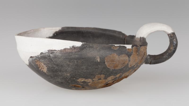 Czerpak o wklęsłym dnie, półkolistym brzuścu, brzegu zaokrąglonym do środka. Wnętrze zdobione odciskiem koła i skośnymi rowkami