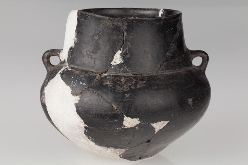 Amfora o baniastym brzuścu, stożkowatej szyjce, zaopatrzona w dwa ucha. Naczynie zdobione dookolnym rowkiem