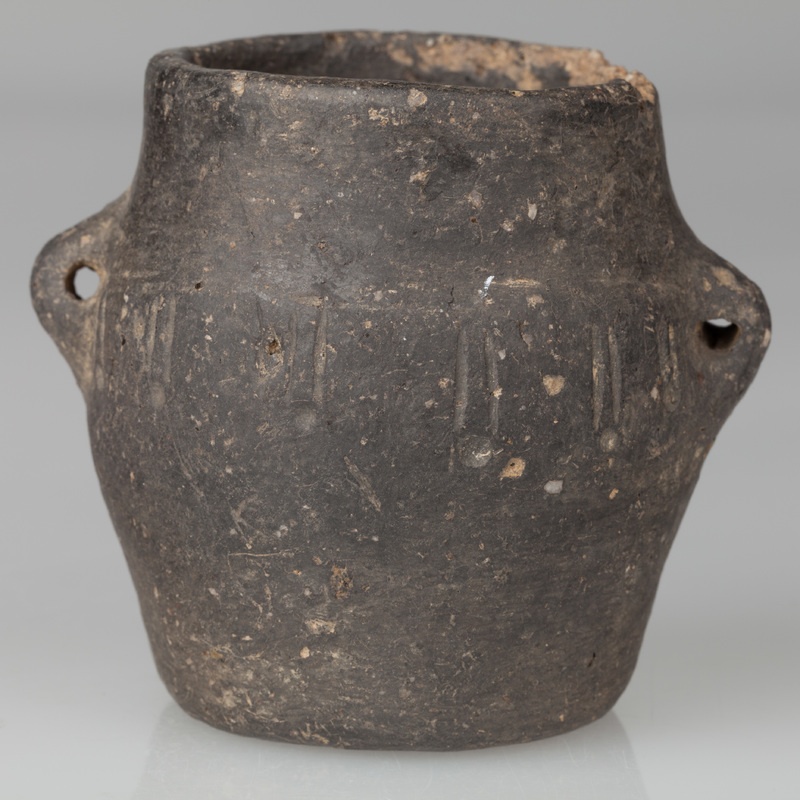 Garnek beczułkowaty, zaopatrzony w dwa kolankowate uszka