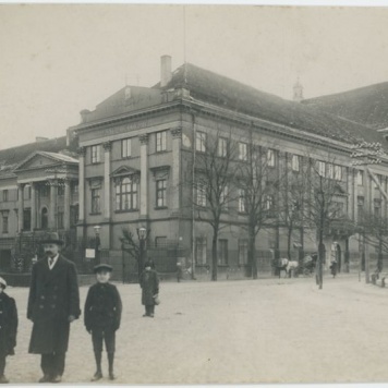 Mężczyzna z dwójką dzieci na tle Pałacu Gubernatorskiego