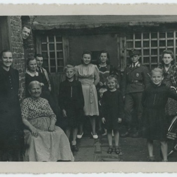 Grupa kobiet i mężczyzn przed domem