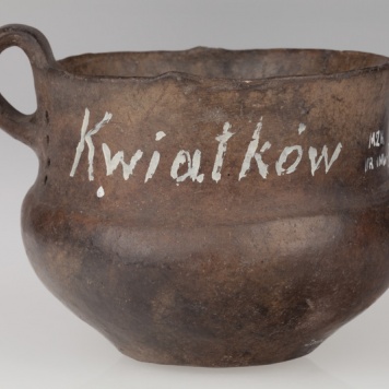 kubek z taśmowatym uchem, obok ucha pionowe rzędy otworków  