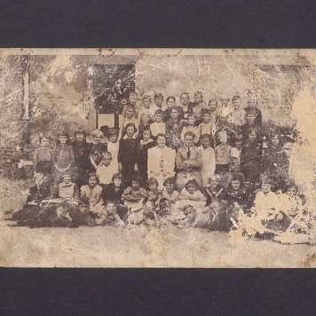 Uczniowie wraz z nauczycielem na tle budynku szkoły w Gnieźnie.